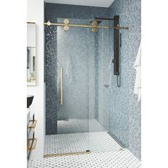 a bathroom with blue and white tile, gold fixtures and a glass shower stall door