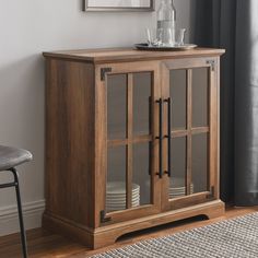 a wooden cabinet with glass doors on the front and bottom, next to a chair