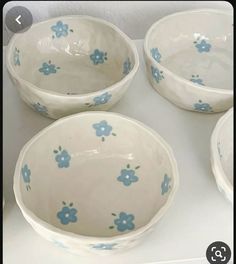 four bowls with blue flowers on them sitting on a white counter top next to each other