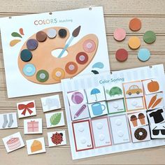 an assortment of color matching cards and magnets on a wooden table with paintbrushes