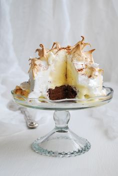 a cake with white frosting and chocolate toppings on a glass plate, ready to be eaten