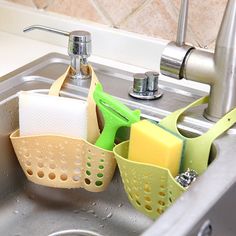 three sponges and two kitchen gadgets in a stainless steel sink under a faucet