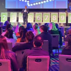 a man standing on top of a stage in front of an audience at a conference