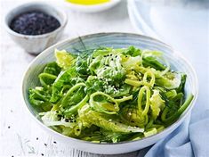 a white bowl filled with green vegetables on top of a table