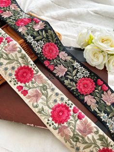 two pieces of cloth with flowers on them sitting next to some scissors and flower bouquets