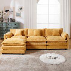 a living room with a large sectional couch and rugs on the floor in front of a window