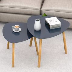 two coffee tables sitting on top of each other in front of a couch with a book