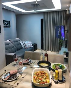 a living room filled with furniture and plates of food on top of a wooden table