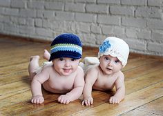 two babies laying on the floor wearing hats