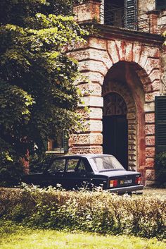 a car parked in front of a building with green shutters on it's windows