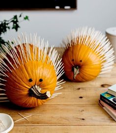 two orange pumpkins with spikes on them sitting on a wooden table next to books