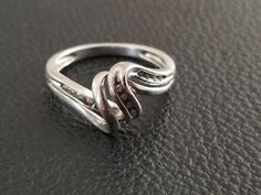 Sterling silver swirl ring with diamonds. The ring is a US size 6 3/4. It contains 12 diamonds at 0.005 cts for a total of 0.06 cts. The diamond has swirled middle and the diamonds are mounted to the right and left and to one part of the swirl. This will make a lovely gift for a special person as a promise, anniversary or friendship ring. Silver Bypass Ring With Diamond Accents For Gift, Silver Bypass Ring With Diamond Accents, Fine Jewelry Silver Bypass Ring With Diamond Accents, Silver Bypass Ring With Diamond Accents For Anniversary, Silver Bypass Ring With Diamond Accents For Formal Occasions, Formal Silver Bypass Ring With Diamond Accents, Friendship Ring, Friendship Rings, Swirl Ring