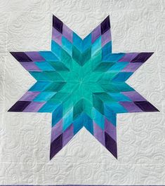 a blue and purple star quilted on top of a white wall