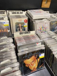 many cds are stacked on top of each other in this store display case, with the covers pulled back