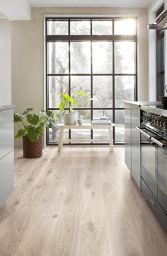 a kitchen with wood flooring and stainless steel appliances in front of a large window