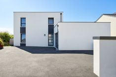 an empty driveway in front of a white building