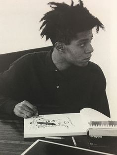 a man with dreadlocks sitting at a desk in front of an open book