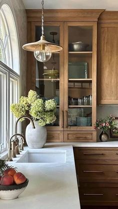 a kitchen filled with lots of wooden cabinets and white counter tops next to a window