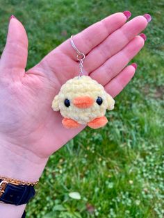 a hand holding a small stuffed animal keychain in it's right hand