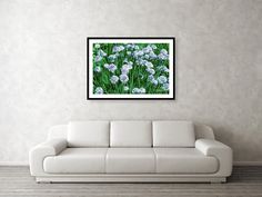 a living room with a white couch and painting on the wall above it that has blue flowers