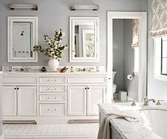 a white bathroom with two sinks, mirrors and a bathtub in the middle of it