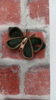 a small green butterfly brooch sitting on top of a brick wall