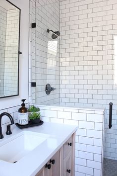 a white tiled bathroom with black faucet and sink