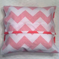 pink and white chevroned pillow with red ribbon on the side, sitting on a bed