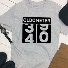 an oldometerer shirt sitting on top of a table next to some shoes and a hat