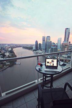 a laptop computer sitting on top of a table next to a window overlooking a city