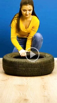 a woman sitting on the floor next to a tire