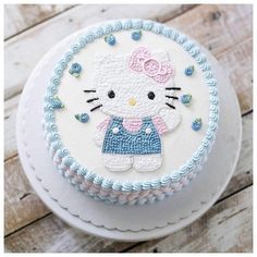 a hello kitty cake with blue and white frosting on it's side, sitting on a wooden table