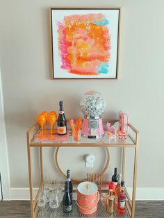 a cute gold bar cart with orange and pink accents. Funky Bar Cart Decor, Bar Cart Picture Frame, College Bar Cart Decor, Bar Cart Items, Bar Cart In Apartment, Decorative Bar Cart, Pink Bar Cart Aesthetic, Bar Cart Simple