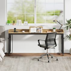 an office with a desk, chair and potted plant in front of the window