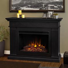 a fire place in a living room with candles on the mantle and pictures above it