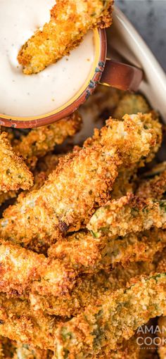 some fried food is in a bowl with ranch dressing on the side and dipping sauce