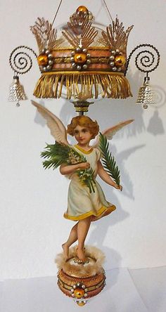 an angel figurine holding a bunch of green leaves on top of a table