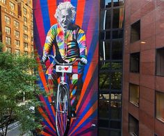 a bicycle parked in front of a building with a painting on it's side