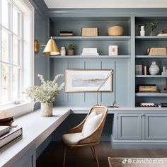 a home office with blue painted walls and built - in shelving, white flowers on the desk