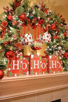 a christmas tree decorated with red and green presents in front of a fireplace mantel