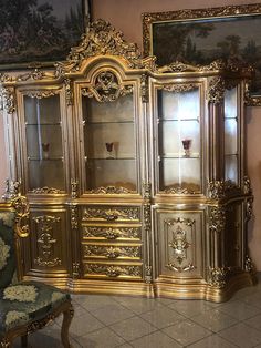 an ornate gold painted china cabinet with glass doors and carvings on the front, in a living room