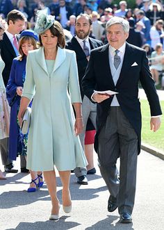 the couple are walking down the street in suits and hats, one is wearing a blue coat