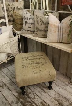 an old chair and ottoman are on display in a room filled with pillows, cushions and other items