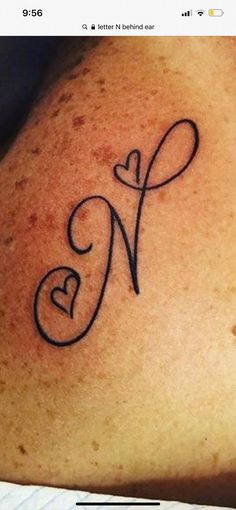 a woman's lower back tattoo with the letter n in cursive font