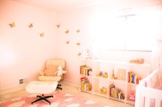 a baby's room with a chair, book shelf and bookshelf