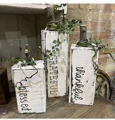 three wooden boxes with plants in them sitting on a table next to a brick wall