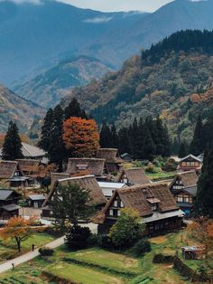 an aerial view of a village with mountains in the back ground and trees on either side