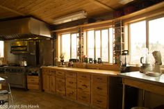 a large kitchen with wooden cabinets and stainless steel appliances on the counter top, along with windows that look out onto mountains