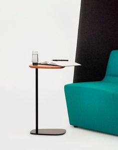 a table with a glass on it next to a blue chair and a black wall