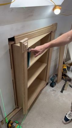 a man is working on an unfinished bookcase with green light coming from the bottom